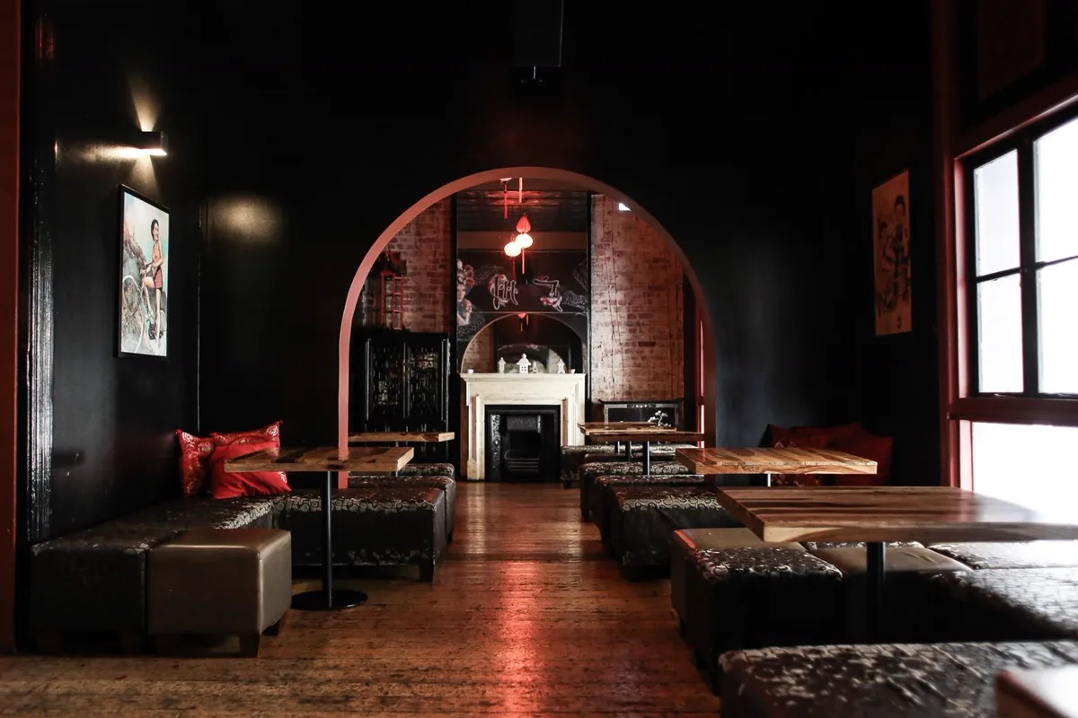 Salle d'un club aux murs sombres, banquettes et lumière tamisée